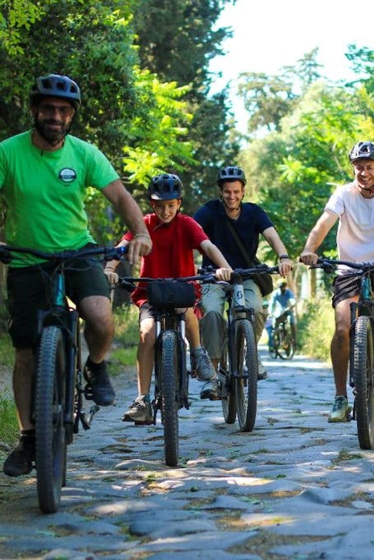 Family riding mountain bikes on a cobblestone path through lush green countryside
